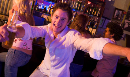 Young man in nightclub approaching camera with arms outstretched